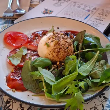 Burrata on green leaves and sliced tomatoes